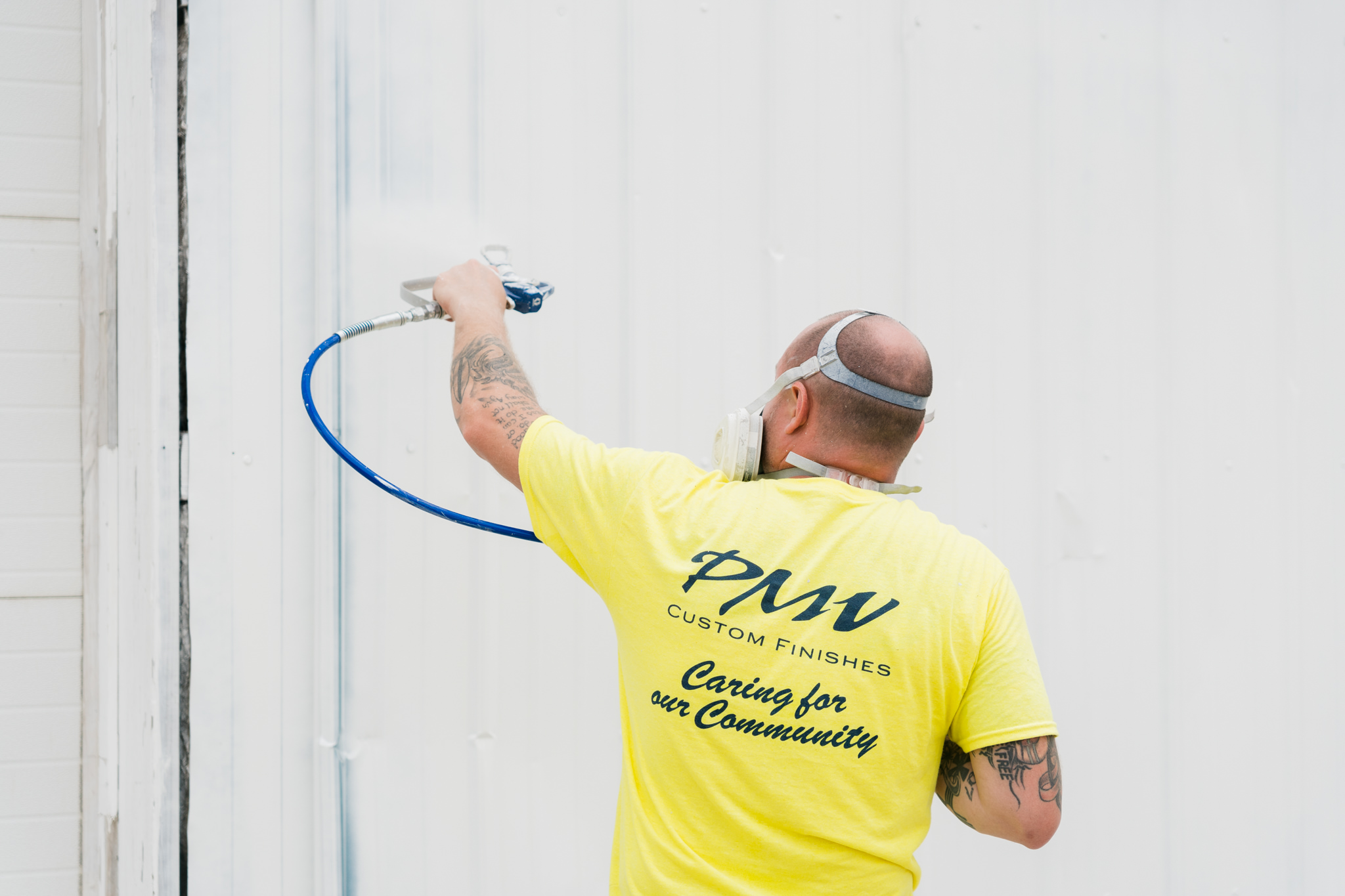 PMV employee spraying siding of building