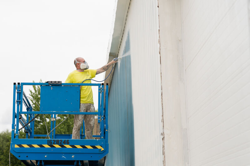 Professional Painter spraying the outside of a commercial building