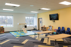 Yellow kids room at a church with play set and table and chairs.