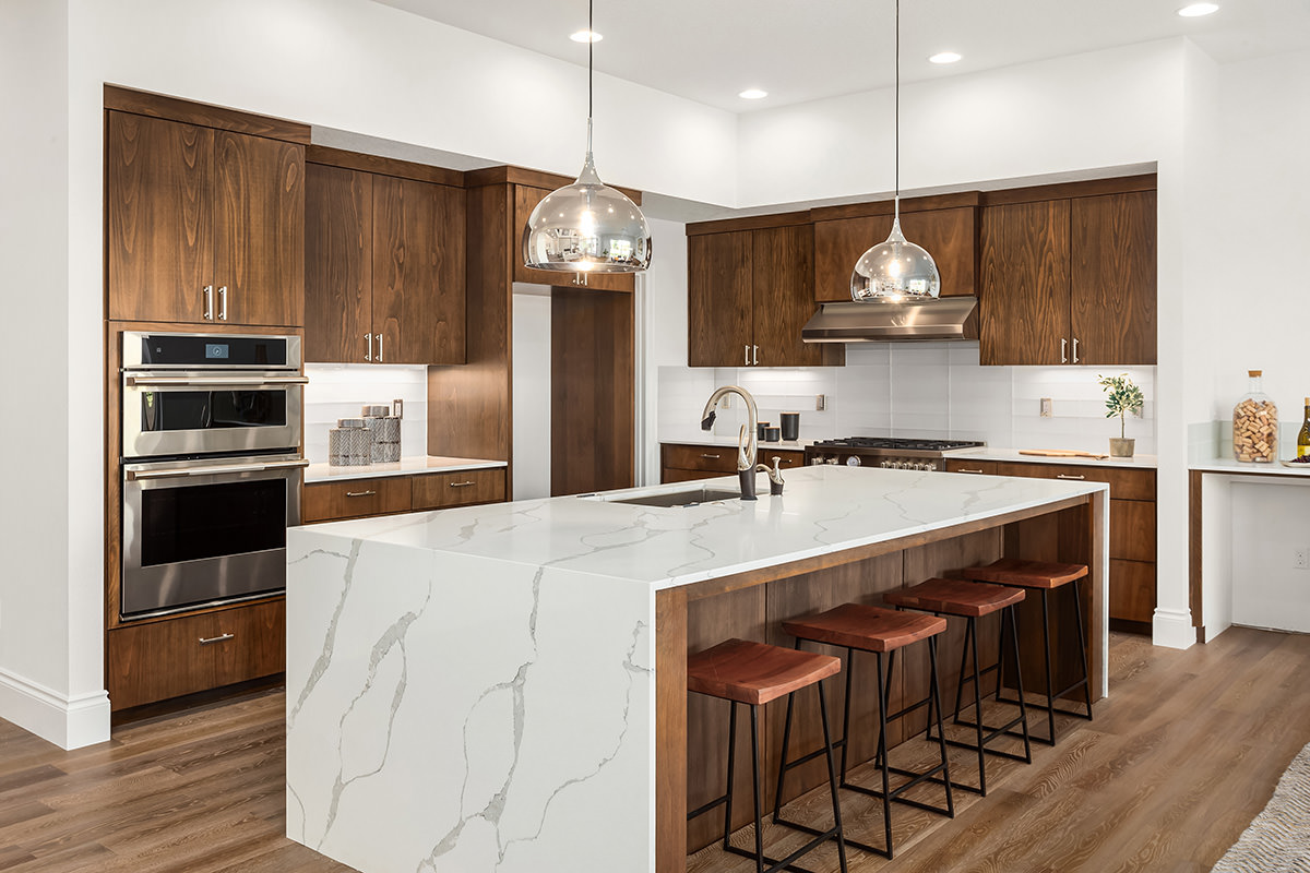 PMV - Blog - Wood Cabinets Are Back 2 Beautiful kitchen with dark wood cabinets and a large quartz island