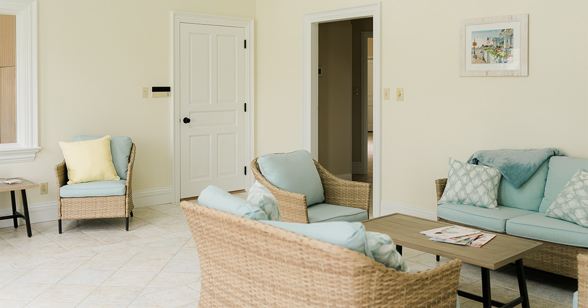 PMV - Project Highlight - Lake Templene Sitting Room 1 Freshly painted sitting room with light tan walls and wicker furniture with light blue cushions.