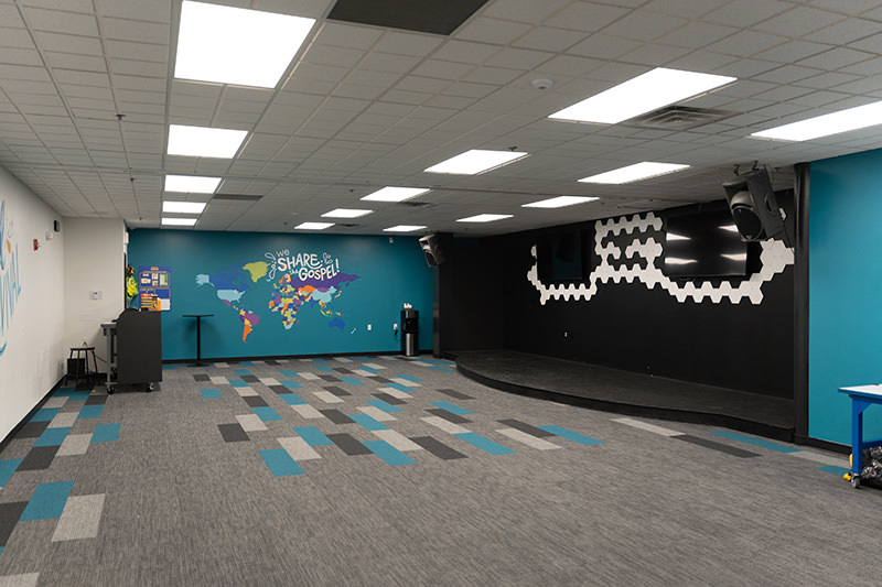 PMV - Project Highlight - Radiant Church Vibrant Colors 1 Blue kids room at a church. Says "We Share the Gospel" on the wall.