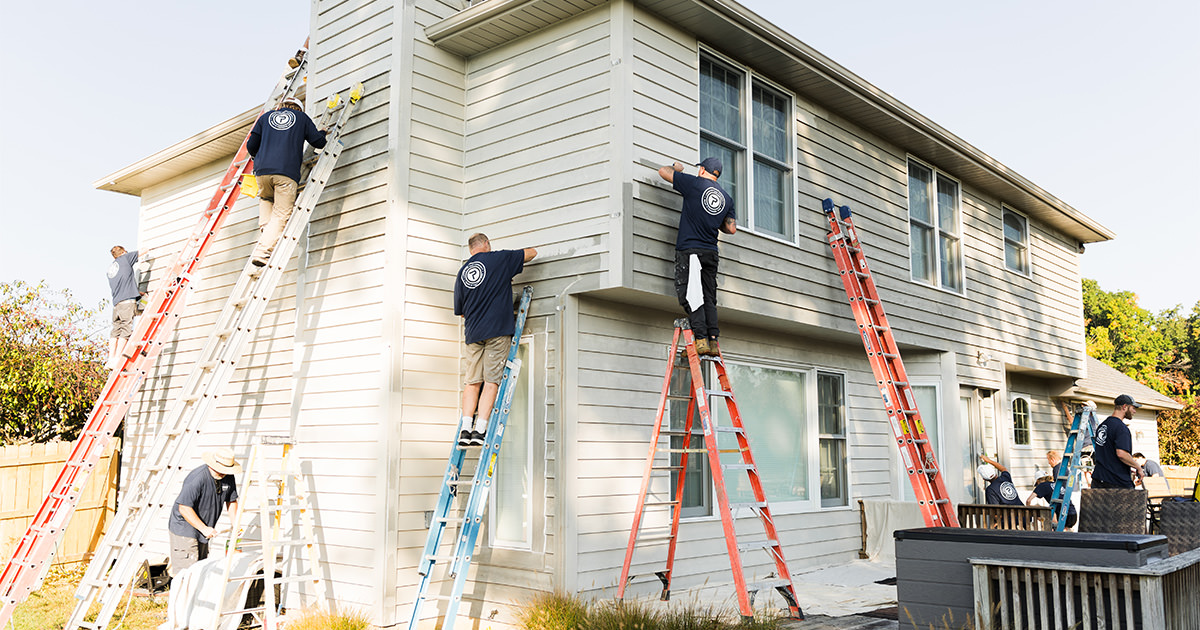 House painters from PMV Painting painting siding and trim during an exterior house repaint project in Portage Michigan