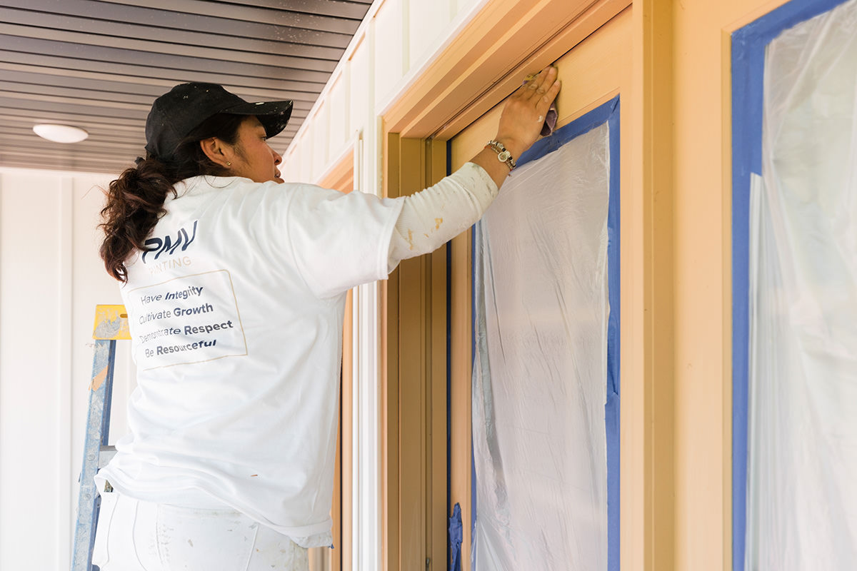 House painter from PMV Painting preparing the exterior of a house for a repaint project in Portage Michigan