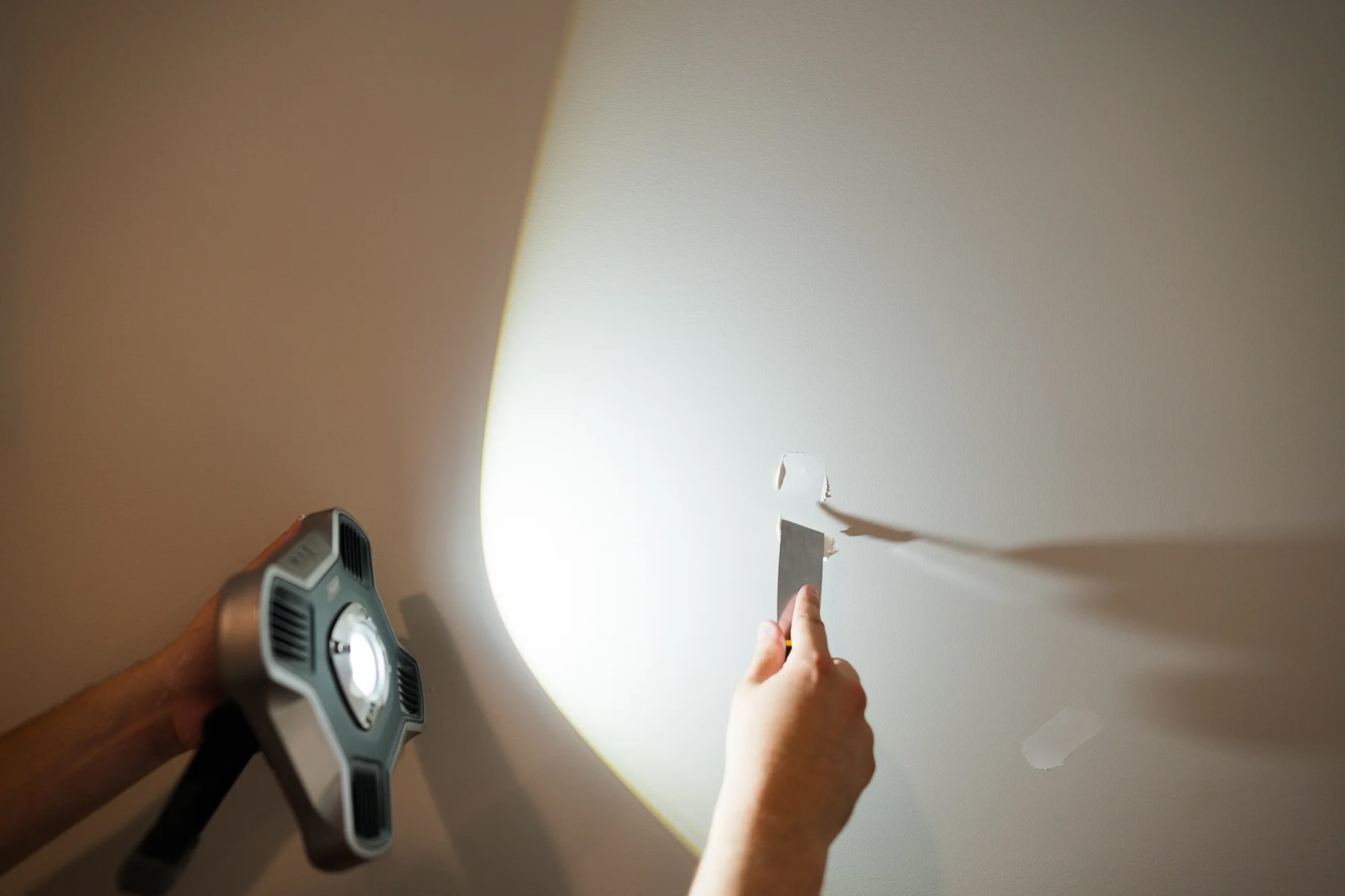 PMV painter using a work light to inspect a painted surface for imperfections